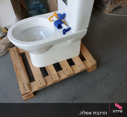 אסלה לבנה על משטח עץ עם חלקי התקנה